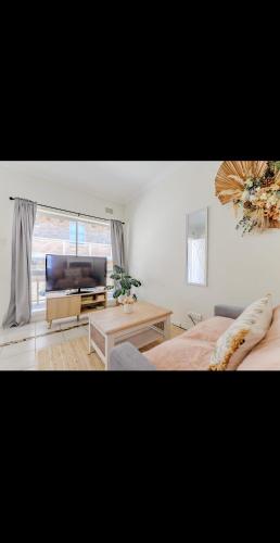 a bedroom with a bed and a television and a table at Top Location Beachside Apartment in Cronulla