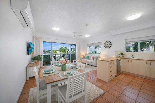 a kitchen and a living room with a table and chairs at Waterfront Apartment Near City, Stadium & Ferry Townsville in Townsville
