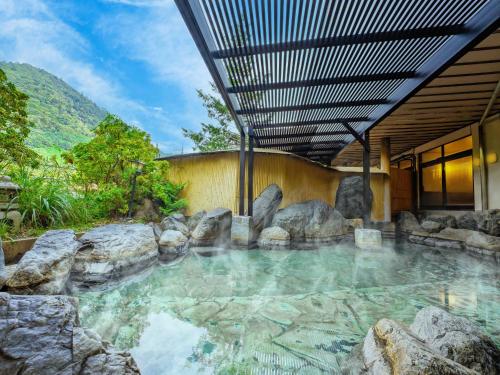 a pool of water with rocks in front of a house at YU-FURI Nasu-Shiobara in Nasushiobara