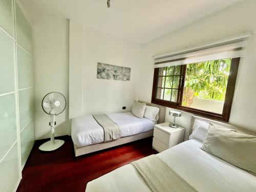 a bedroom with two beds and a window and a fan at VILLAMOCANES in Frontera