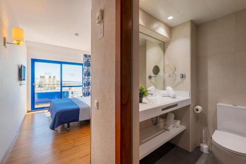 a bathroom with a sink and a toilet and a window at Hotel Tahití Playa & Suites 4Sup in Santa Susanna