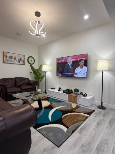 a living room with a couch and a flat screen tv at Maxti Guest Suite, Northwest Calgary in Calgary