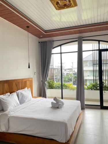 a bedroom with a white bed with a large window at Twin House Villa in Canggu