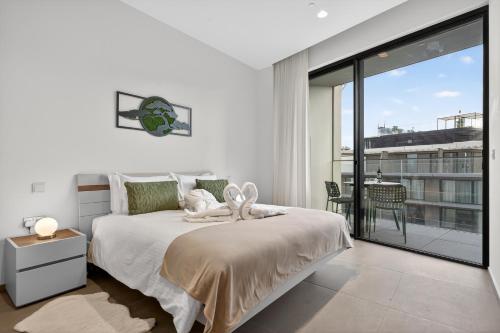 a white bedroom with a bed and a balcony at Urban Heights - Apartment in St Julian's in St. Julianʼs