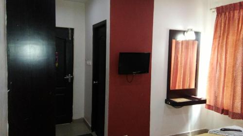 Habitación con puerta y TV en la pared en Sri ArulMuthu Residency, en Madurai