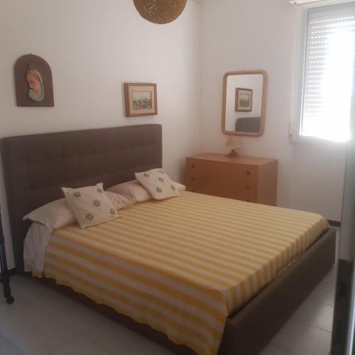 a bedroom with a bed with a yellow and white striped blanket at CONDOMINIO CESANO MARE in Marotta