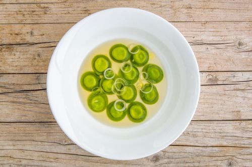a white bowl of jalapenos in a yellow liquid at Locanda Del Pilone in Alba