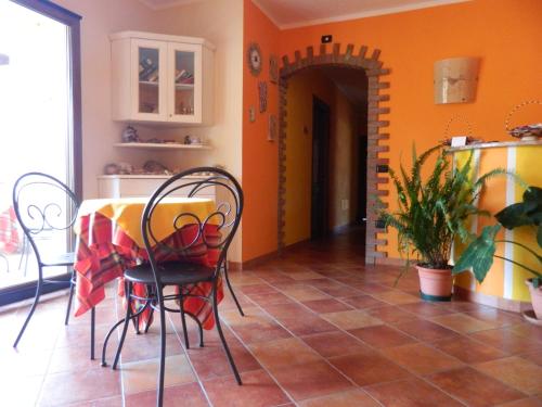 a dining room with a table and chairs and orange walls at Real B&B Primo Sole in Castelsardo