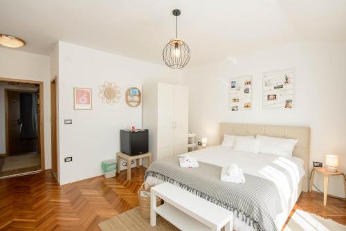 a white bedroom with a bed and a tv at Guests house DaLi in Rovinj