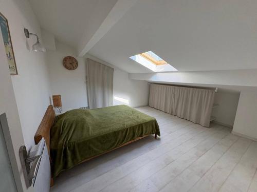 ein Schlafzimmer mit einem Bett, einem Fenster und einer Uhr in der Unterkunft Roq duplex in Valras-Plage