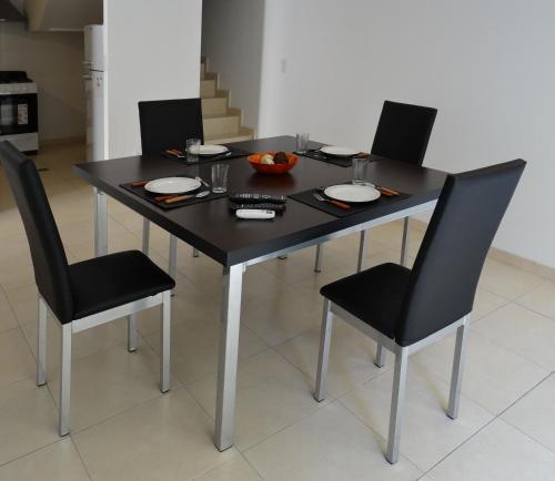 uma mesa preta com quatro cadeiras e uma tigela de fruta em Departamentos Las Cañas em Mendoza