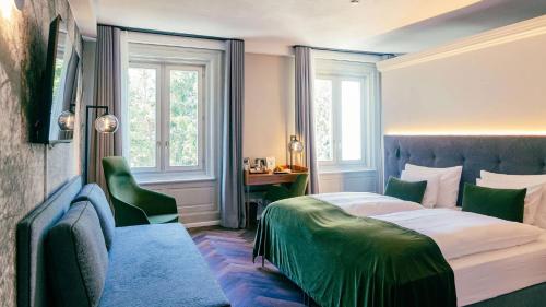 a bedroom with a bed and a desk and windows at Hotel Reine Victoria in St. Moritz