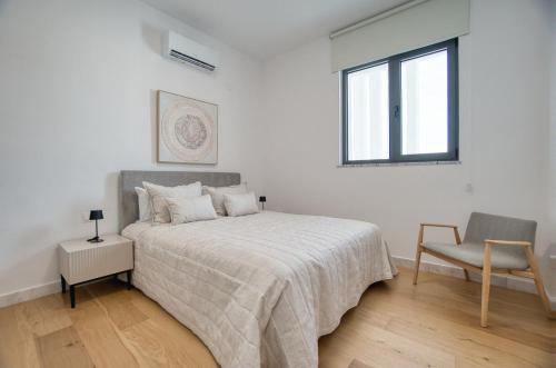 a bedroom with a bed and a chair and a window at Prestige 504 2 BED in Paphos