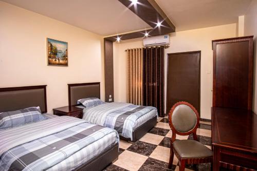 a hotel room with two beds and a chair at Al Riyati Hotel Apartments in Aqaba