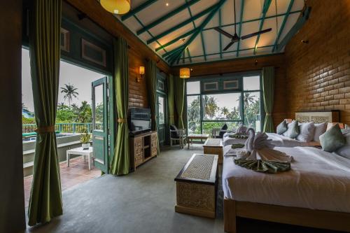 a bedroom with two beds and a balcony with a television at Hiriketiya Beach Resort in Hiriketiya