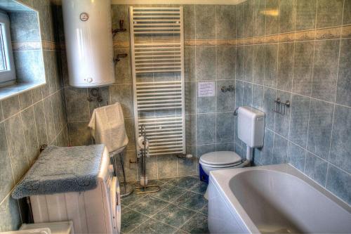 a bathroom with a tub and a toilet and a sink at Apartman Anka in Ratkovica