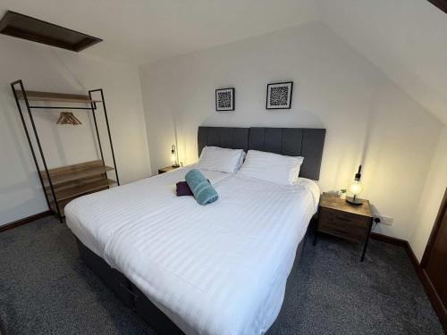 a bedroom with a large white bed with a blue pillow on it at Millbrook House Apartments 7 in Milton