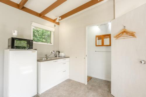 a kitchen with a sink and a microwave at Stoneybrook Cabins in Waimauku
