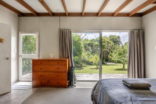 a bedroom with a bed and a dresser and a window at Stoneybrook Cabins in Waimauku