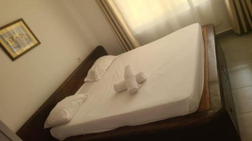 a bed with two pillows on it in a room at Mena apartment in Malindi