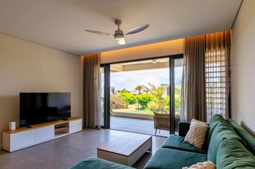a living room with a green couch and a flat screen tv at Asmara Alora E3 - Beachfront in Rivière Noire