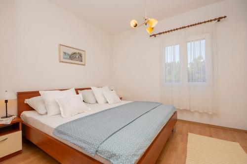 a bedroom with a bed with white walls and a window at Nika Vacation House in Zavojane