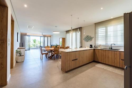 a kitchen with wooden cabinets and a dining room at Asmara Alora E3 - Beachfront in Rivière Noire