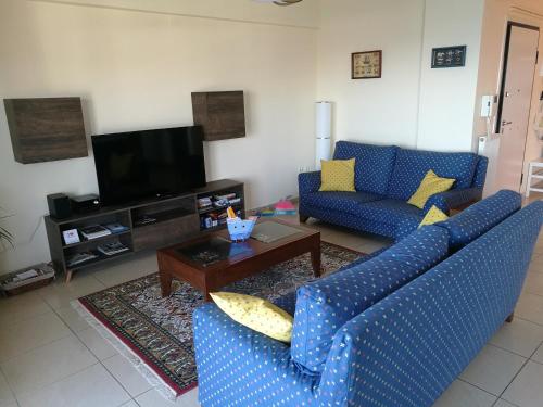 a living room with two blue couches and a tv at Seafront Family Apartment & free parking, the Cruiseflat in Thessaloniki