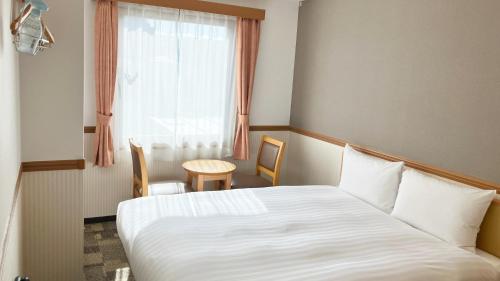 a hotel room with a bed and a table and a window at Toyoko Inn Kagoshima Temmonkan No 2 in Kagoshima