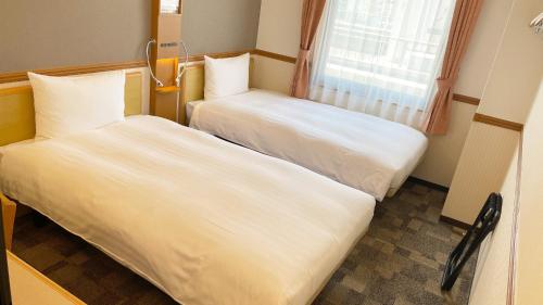 two beds in a small room with a window at Toyoko Inn Kagoshima Temmonkan No 2 in Kagoshima