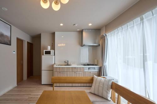 a small kitchen with a table and a refrigerator at Niseko Town Retreat AMBER in Kutchan
