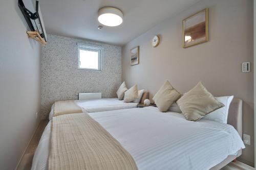 a bedroom with two beds with white sheets at Niseko Town Retreat AMBER in Kutchan