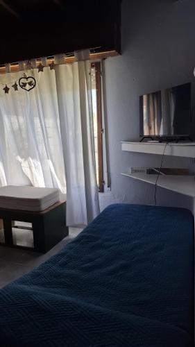 a bedroom with a bed and a tv and a window at Casa en Claromecó in Balneario Claromecó