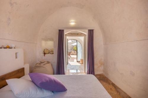 a bedroom with a bed with purple and white pillows at Masseria De Li Travaj - Rive del Salento in Patù