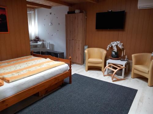 a bedroom with a bed and two chairs and a television at BpR P3 Lodge Apartment with A/C in Budapest