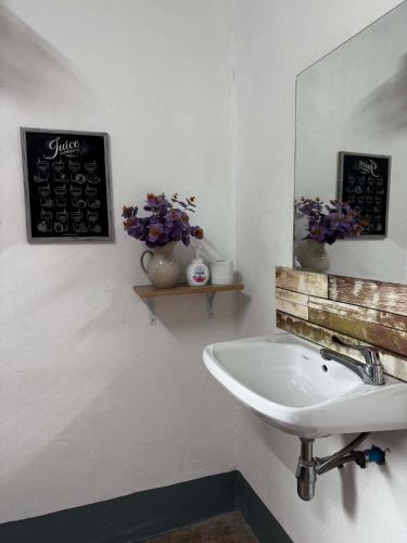 a bathroom with a sink and a mirror and flowers at Baboo Studio in Chiang Dao