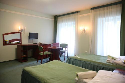 a hotel room with two beds and a desk at Roskosz Zespół Dworsko Parkowy in Biała Podlaska