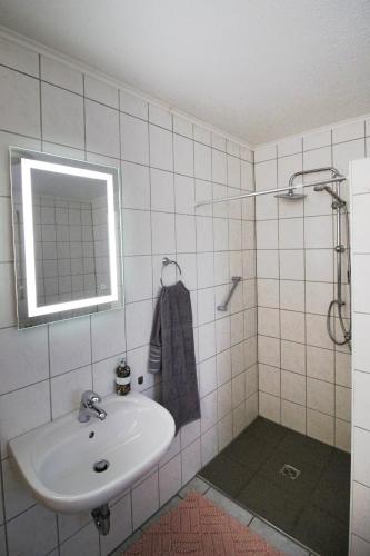 a white bathroom with a sink and a mirror at Haus Hönigblick in Wilnsdorf