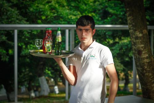 a man holding a tray with bottles and glasses at Vilesh Palace Hotel in Masallı