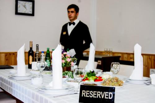 a man in a tuxedo standing in front of a table at Vilesh Palace Hotel in Masallı