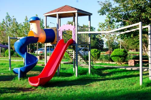a playground with a slide in the grass at Vilesh Palace Hotel in Masallı