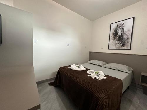 a bedroom with a bed with two towels on it at Suíte Cavalos - Queen's Hotel in Formosa
