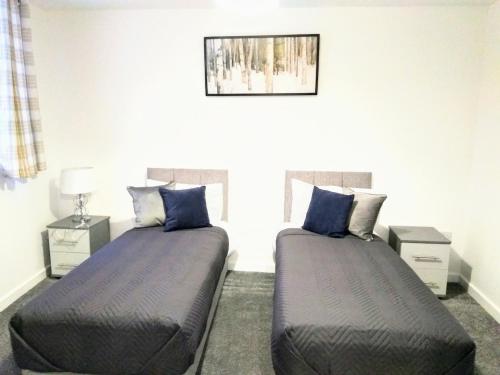 two beds in a bedroom with blue pillows at Sigma Executive Apartment 5 in South Shields