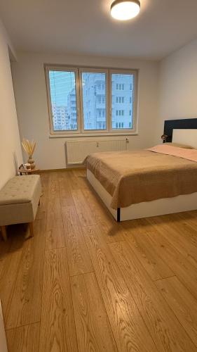 a bedroom with a bed and wooden floors and windows at Prosperity Apartment s parkovaním in Žilina