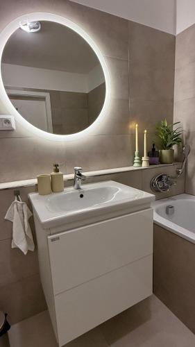 a white bathroom with a sink and a mirror at Prosperity Apartment s parkovaním in Žilina