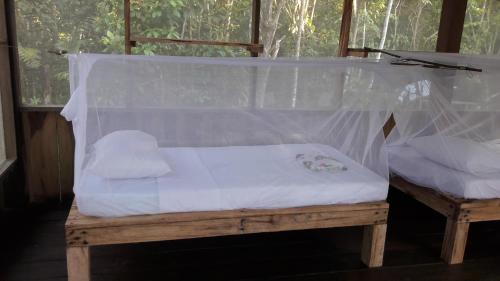 a bed with a net on a wooden bench at Reserva Natural Tucuchira in Santa Sofía