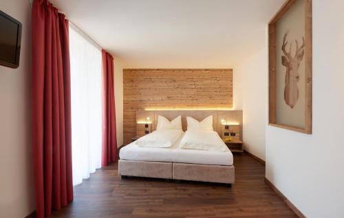a bedroom with a white bed with red curtains at Hotel Al Cervo in Tesero