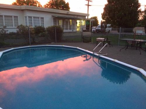 a blue swimming pool in front of a house at Wairoa Motel in Wairoa