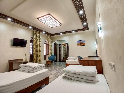 a hospital room with three beds and a desk at AYUB Modern & Heritage HOTEL in Bukhara