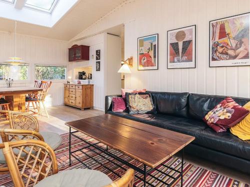 a living room with a black leather couch and a table at 4 person holiday home in Vejby in Vejby